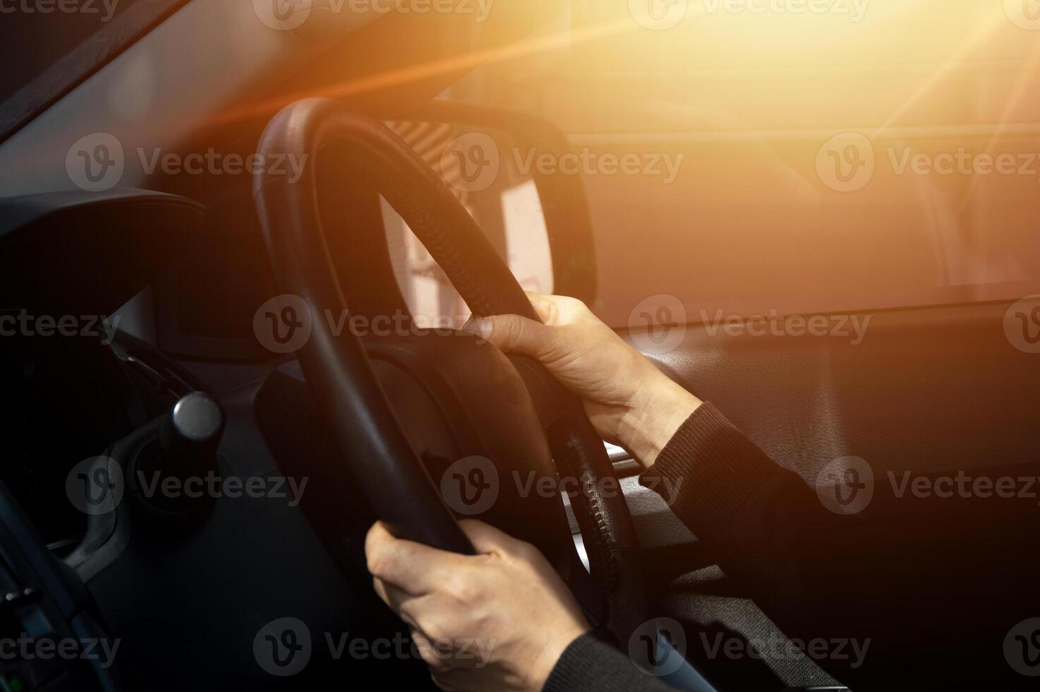 Man driving car, hand on steering wheel, looking at the road ahead,sunset. photo