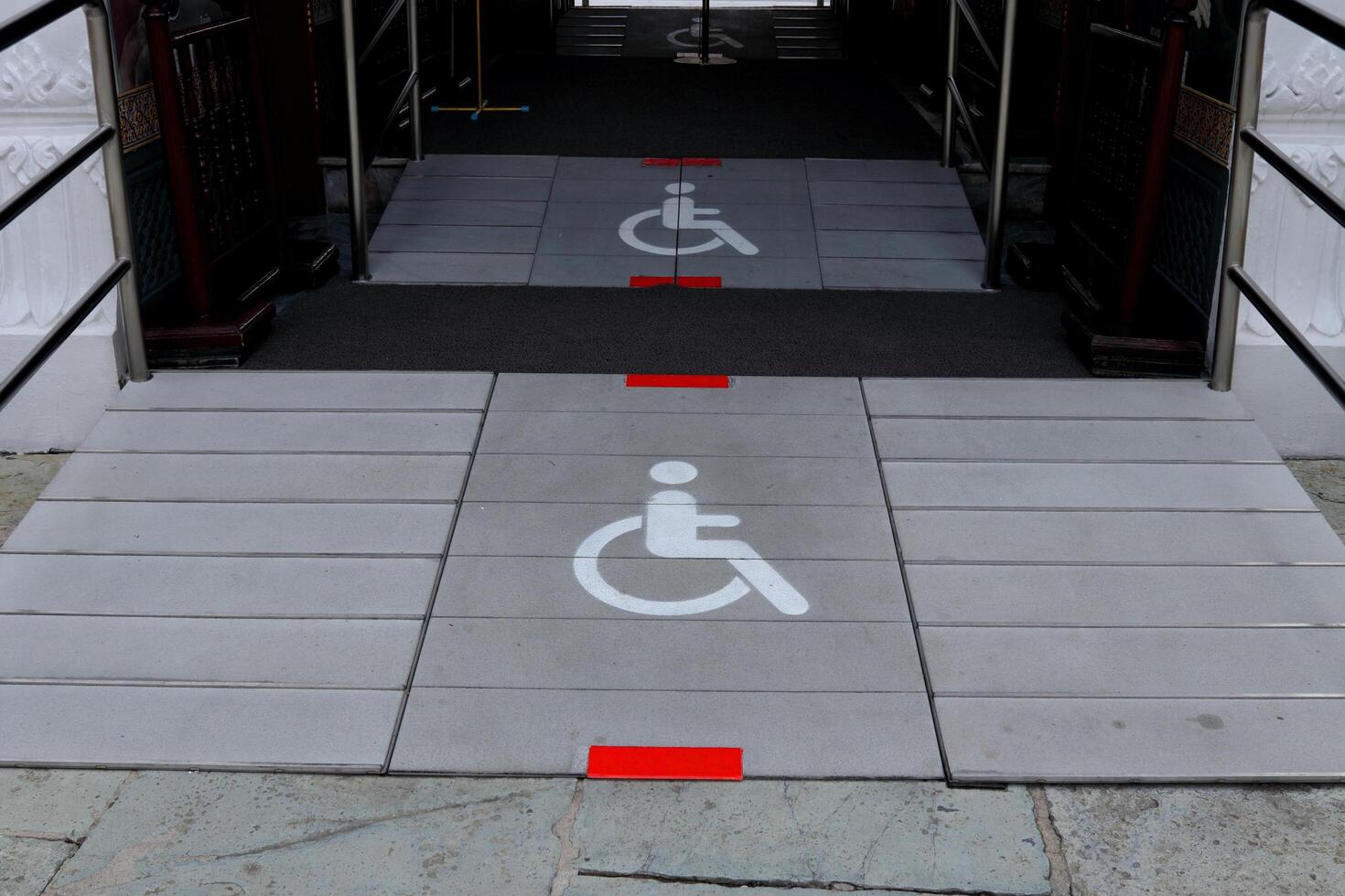 White sign wheelchair on gray slope floor entrance building, Thailand. photo
