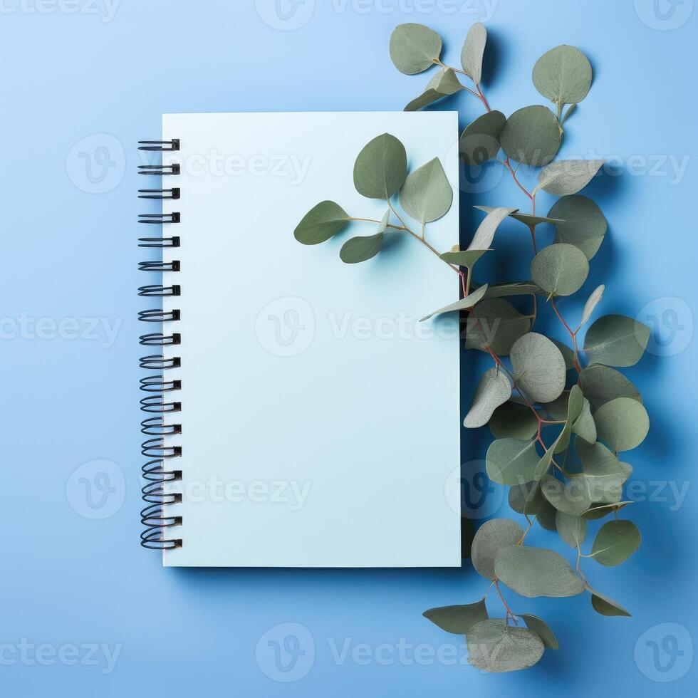 ai generado esmeradamente diseñado azul papel cuaderno adornado con eucalipto hojas en un sereno azul antecedentes. ai generado foto