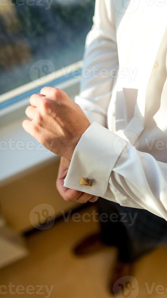Groom wearing cufflink. Handsome young groom going to his wedding photo