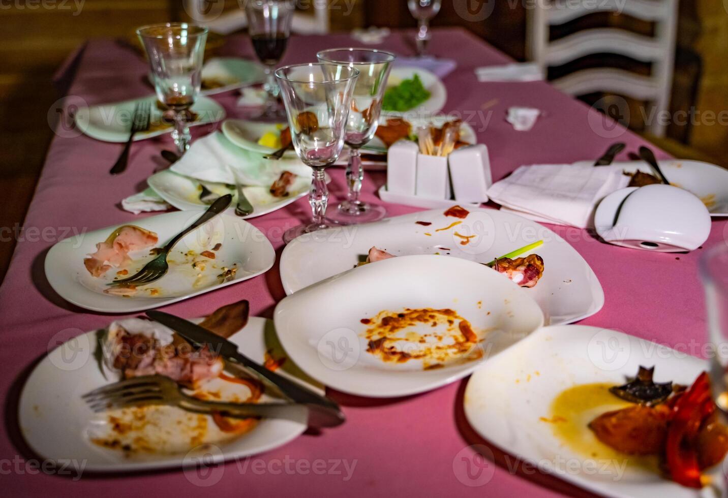 Messy table with dirty dishes after party on food table. Leftover food, empty glasses, dirty dishes on a table. photo