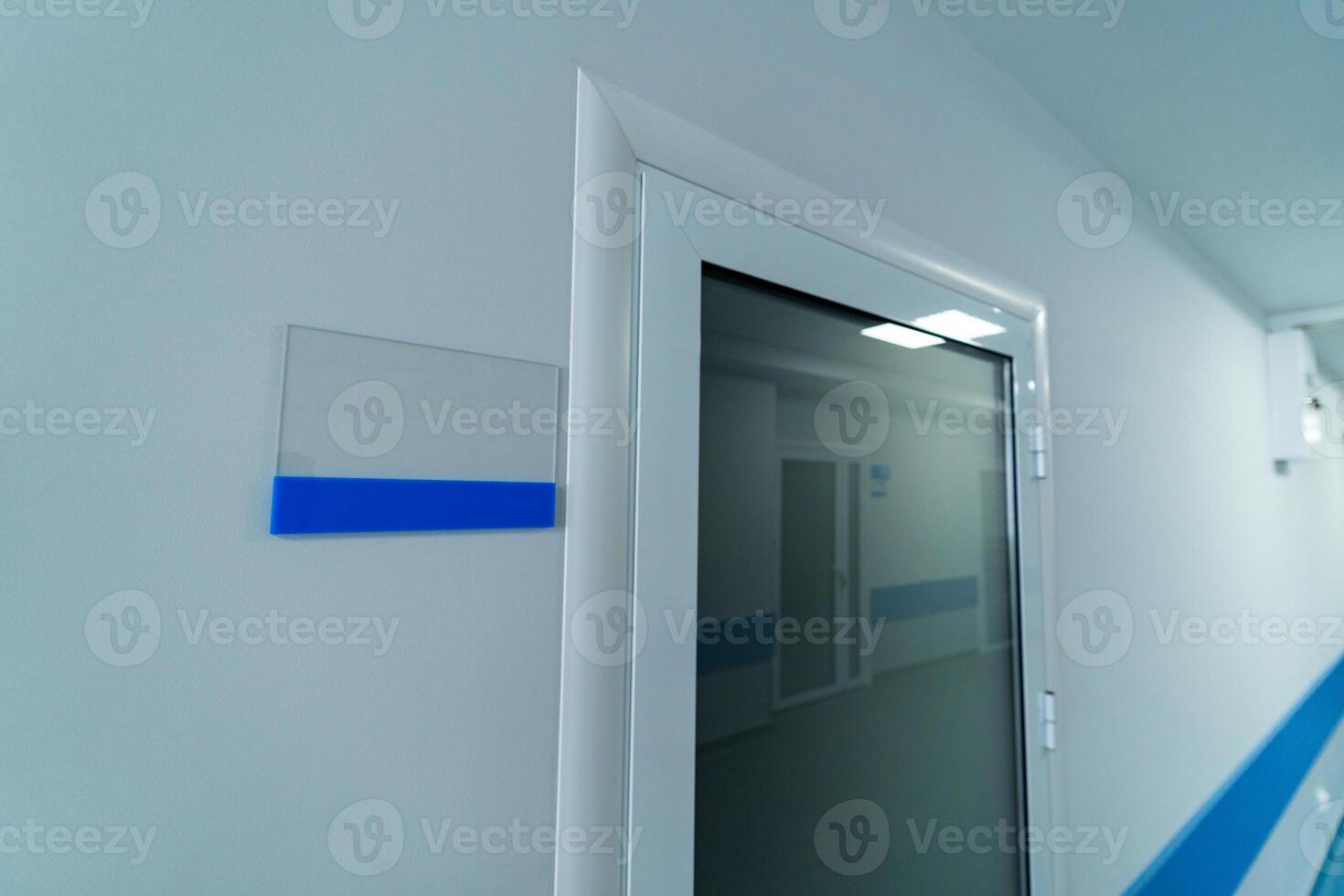 White nameplate near the door. Emergency door in white corridor of hospital. photo