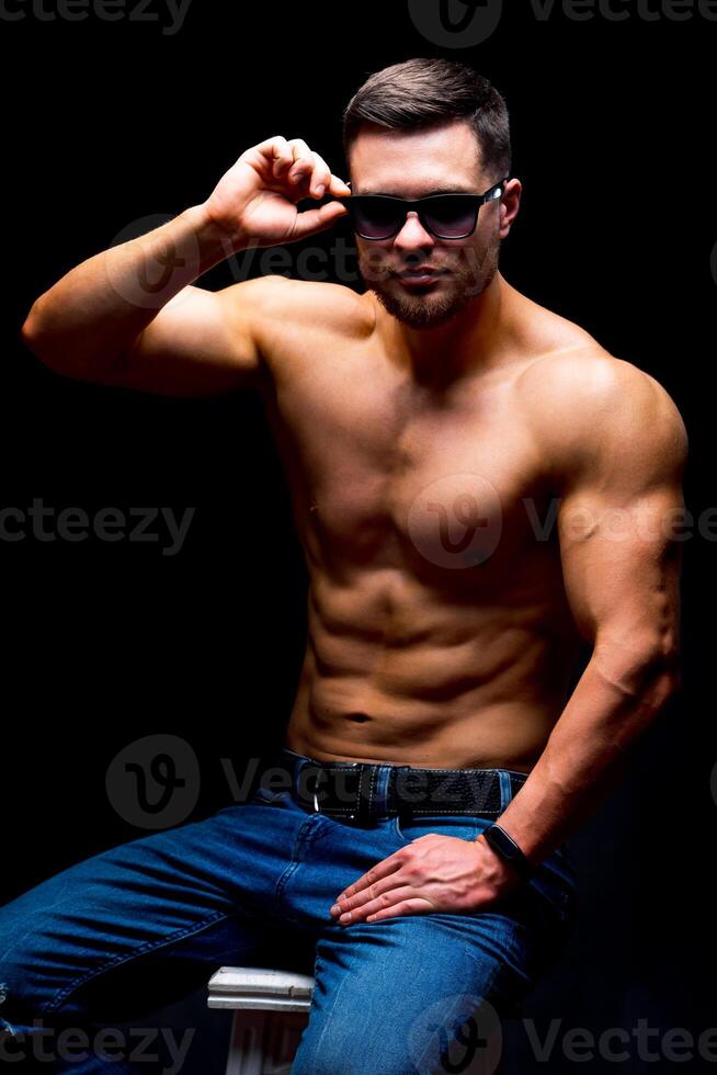 Portrait of a athletic muscular bearded man posing on a black background. photo