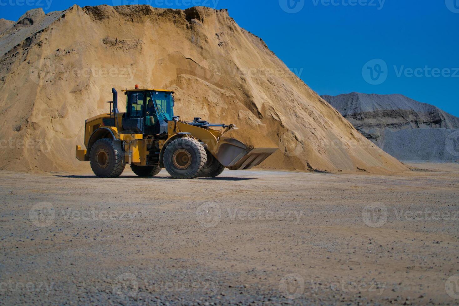 Yellow excavator on a construction site against blue sky photo