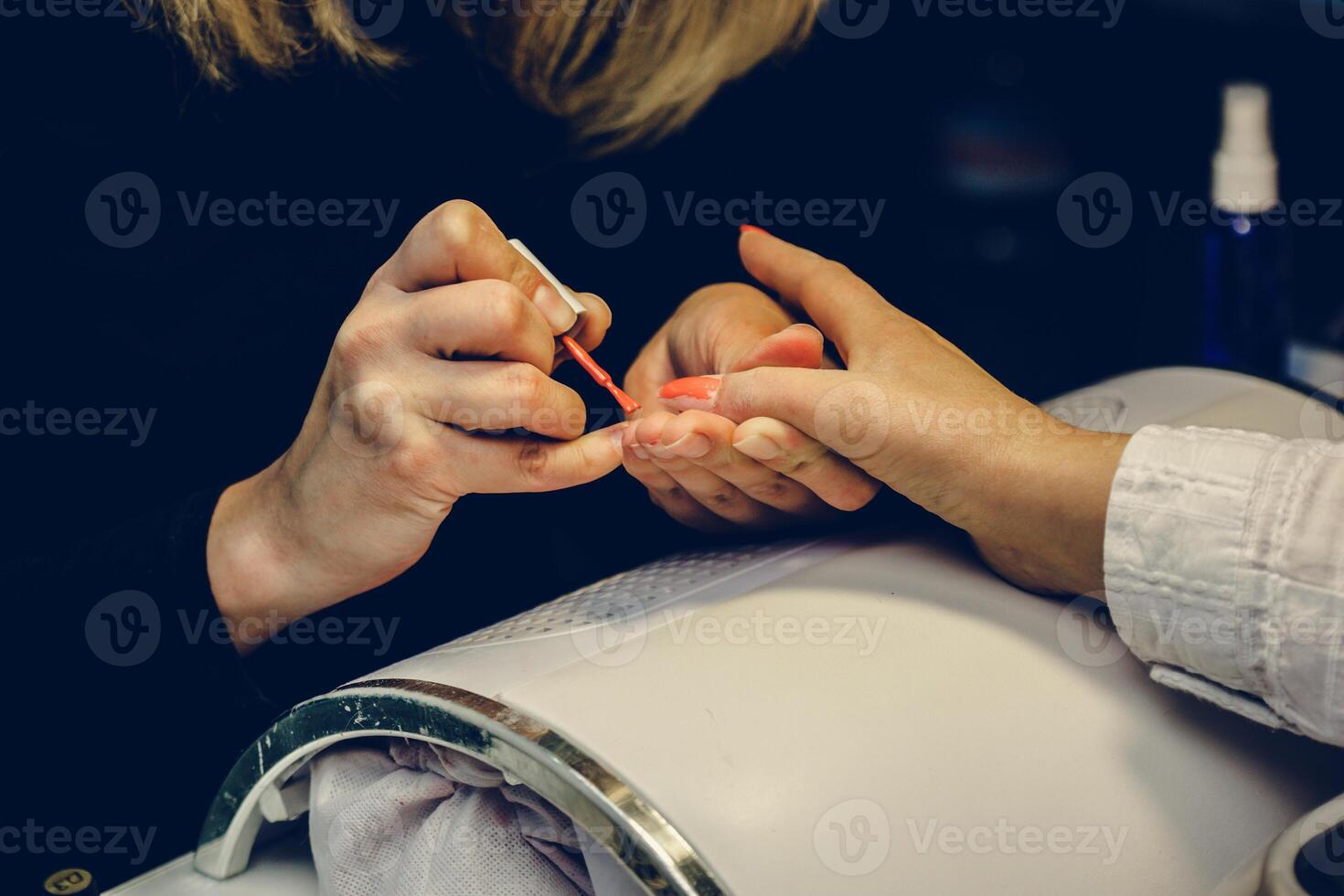 manicuro aplicando rojo uña barniz. manicura Maestro pintura hembra dedo con cerca arriba. manicura y dedos cuidado. foto