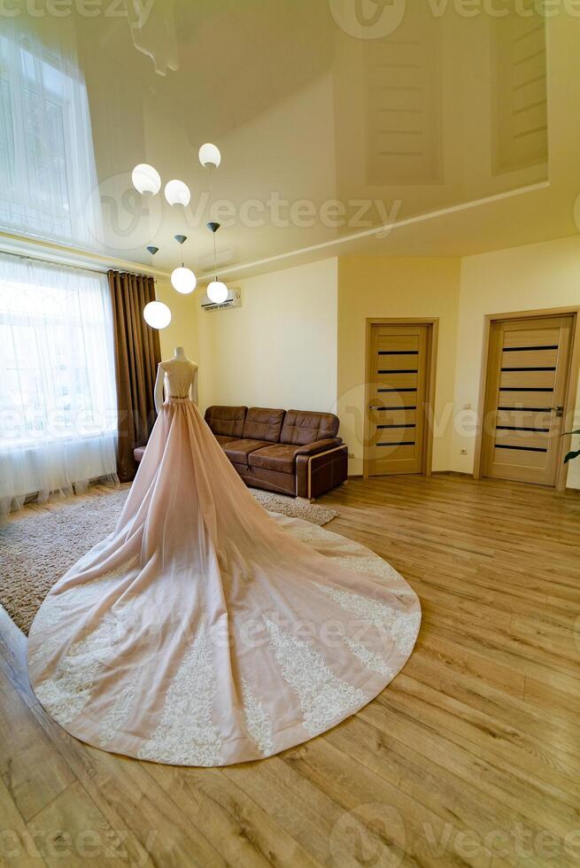 A luxurious wedding dress with lace is on a mannequin in the middle of the room photo