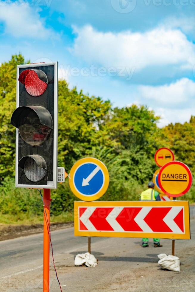 traffic-light shows a red color near the road in the daytime in warm weather on the background of road signs photo