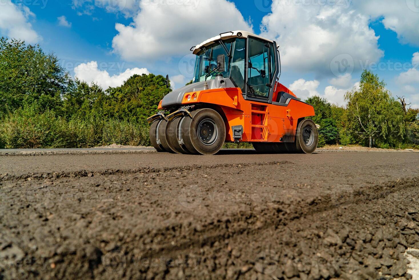 vibrating roller machine compacts asphalt using four hot wheels of rollers on the road. Close-up photo