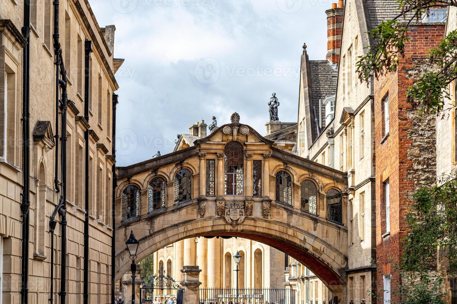 Historic stone bridge connecting two old buildings against a cloudy sky in Oxford, England. photo