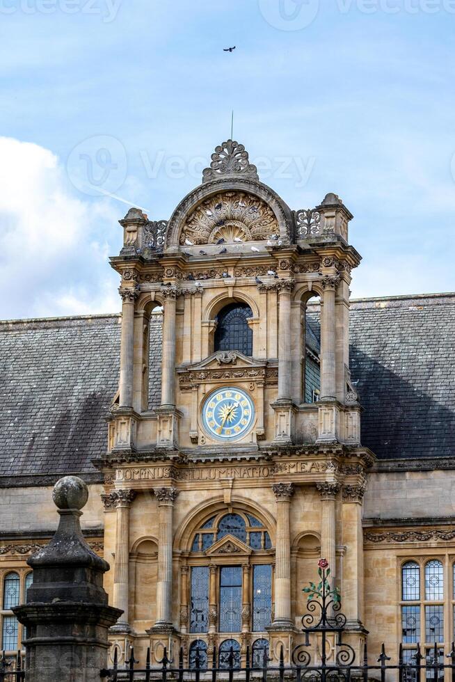 Elegant historical building facade with ornate clock under a blue sky with clouds in Oxford, England. photo