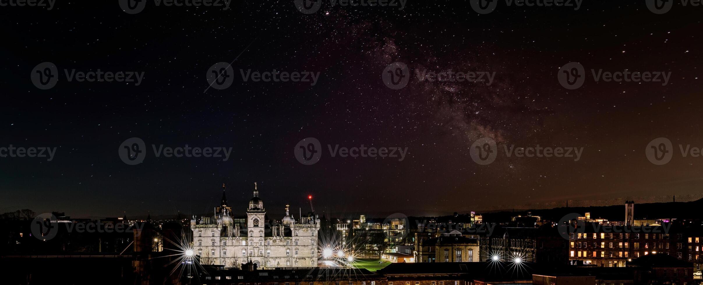 Panoramic night skyline with illuminated buildings under a starry sky featuring the Milky Way in Edinburgh, Scotland. photo