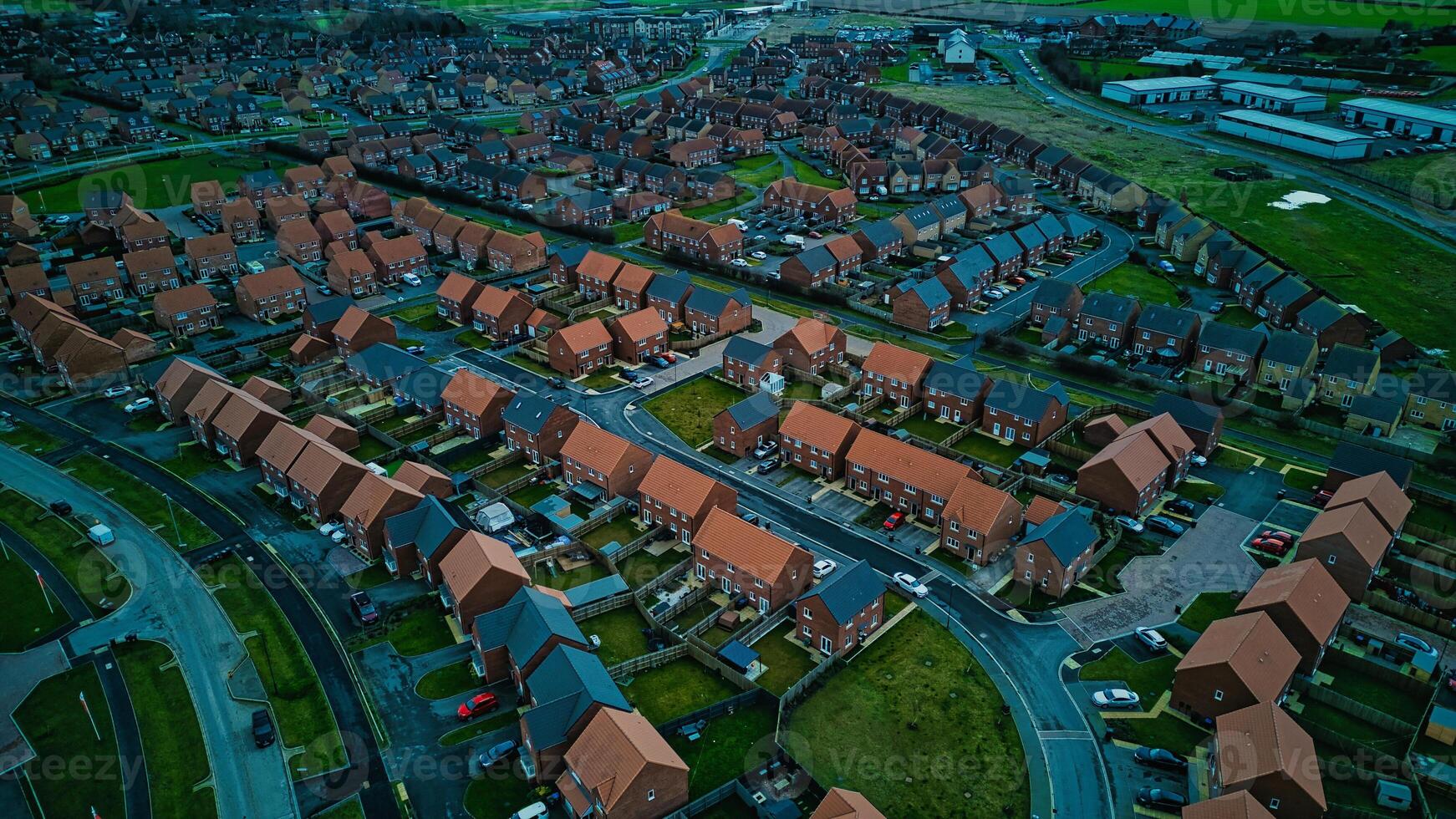 Aerial view of a suburban neighborhood at dusk with rows of houses and green spaces. photo