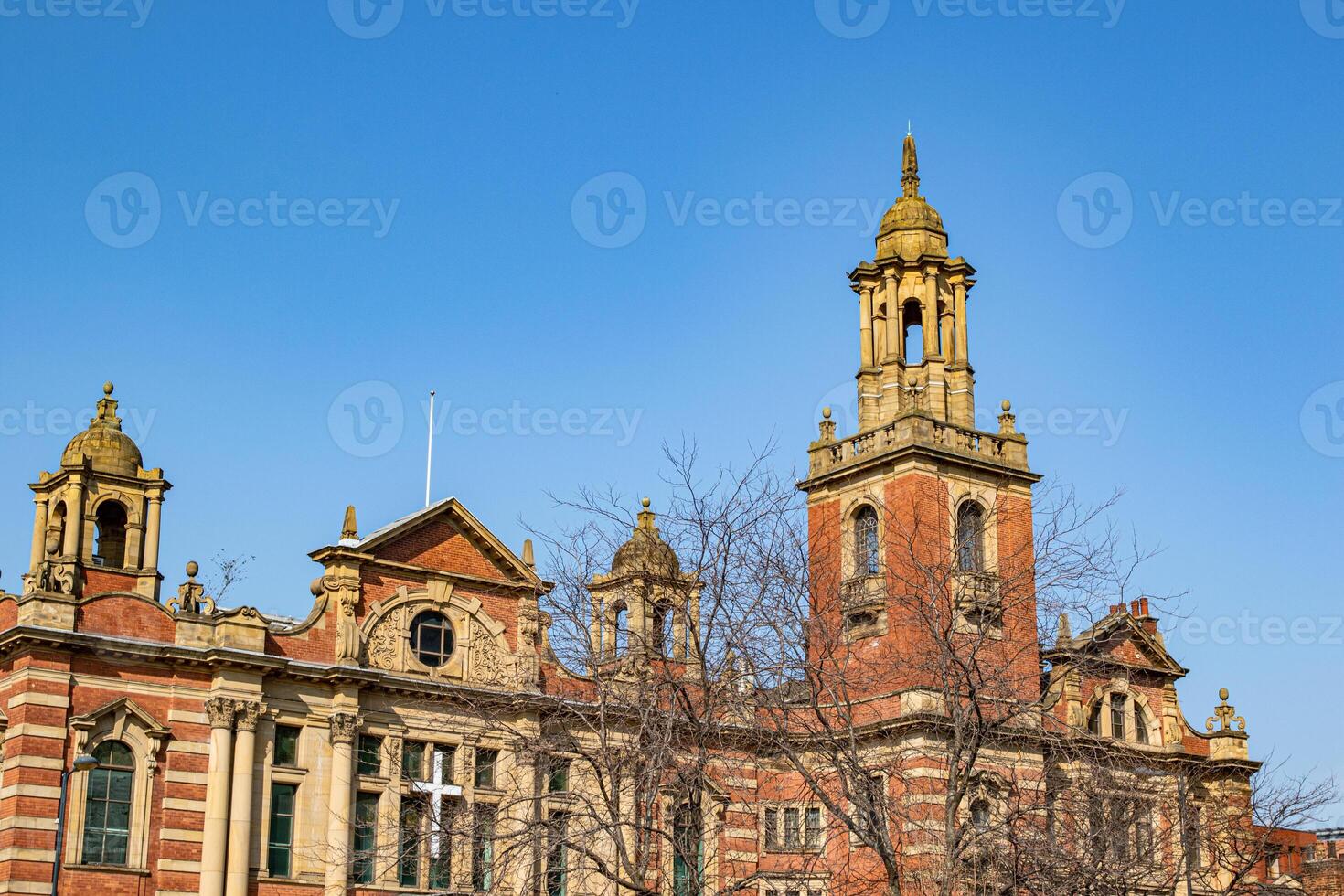 Historic red brick building with clock tower against a clear blue sky in Leeds, England photo