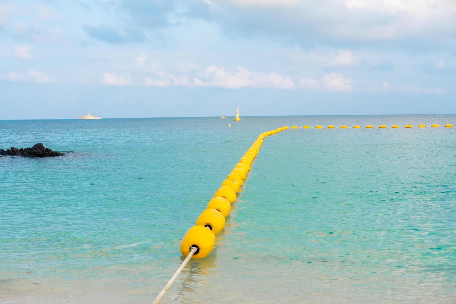 Beautiful views of the beach, sea, rocks during the day with buoys separating the swimming area. photo