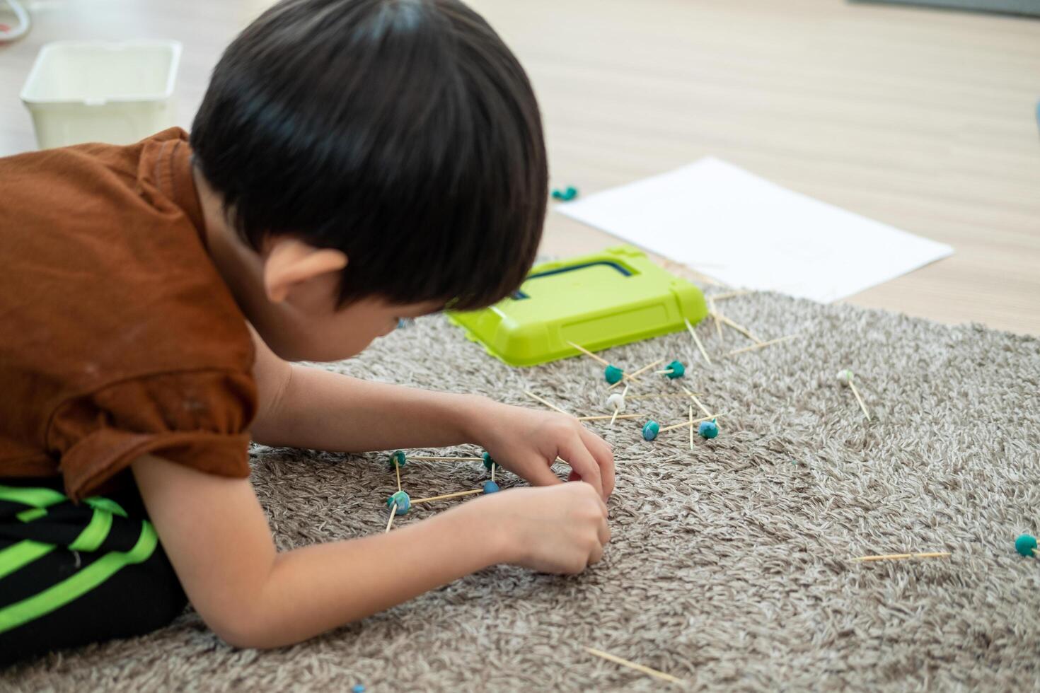 asiático chico jugando con arcilla de moldear en el habitación foto