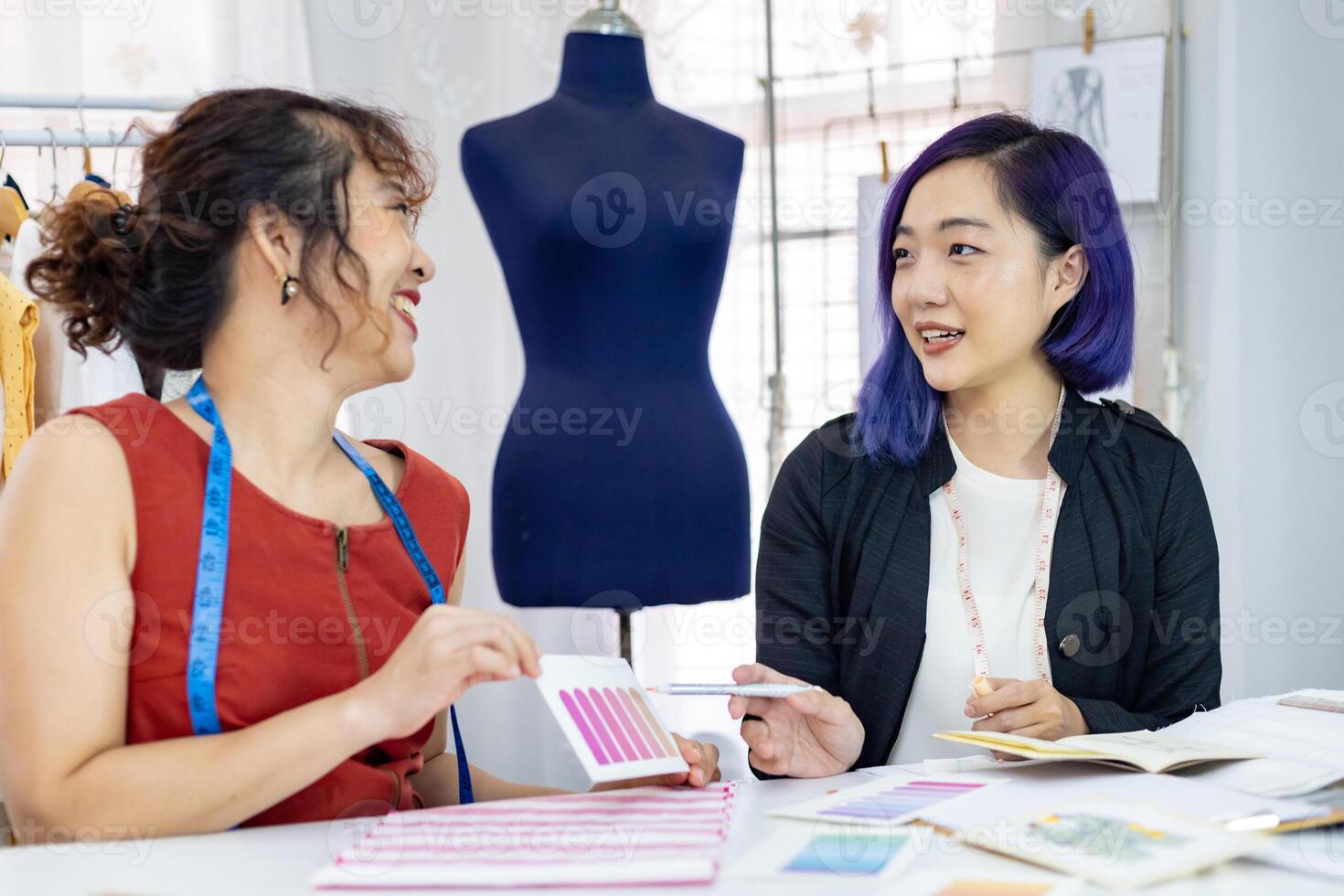 Team of fashionable freelance dressmakers choosing design and pantone for new custom made dress while working in artistic workshop studio for fashion design and clothing business industry photo