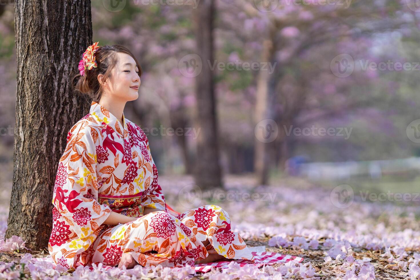 Japanese woman in kimono dress is doing meditation under sakura tree during cherry blossoming season for inner peace, mindfulness and zen practice photo