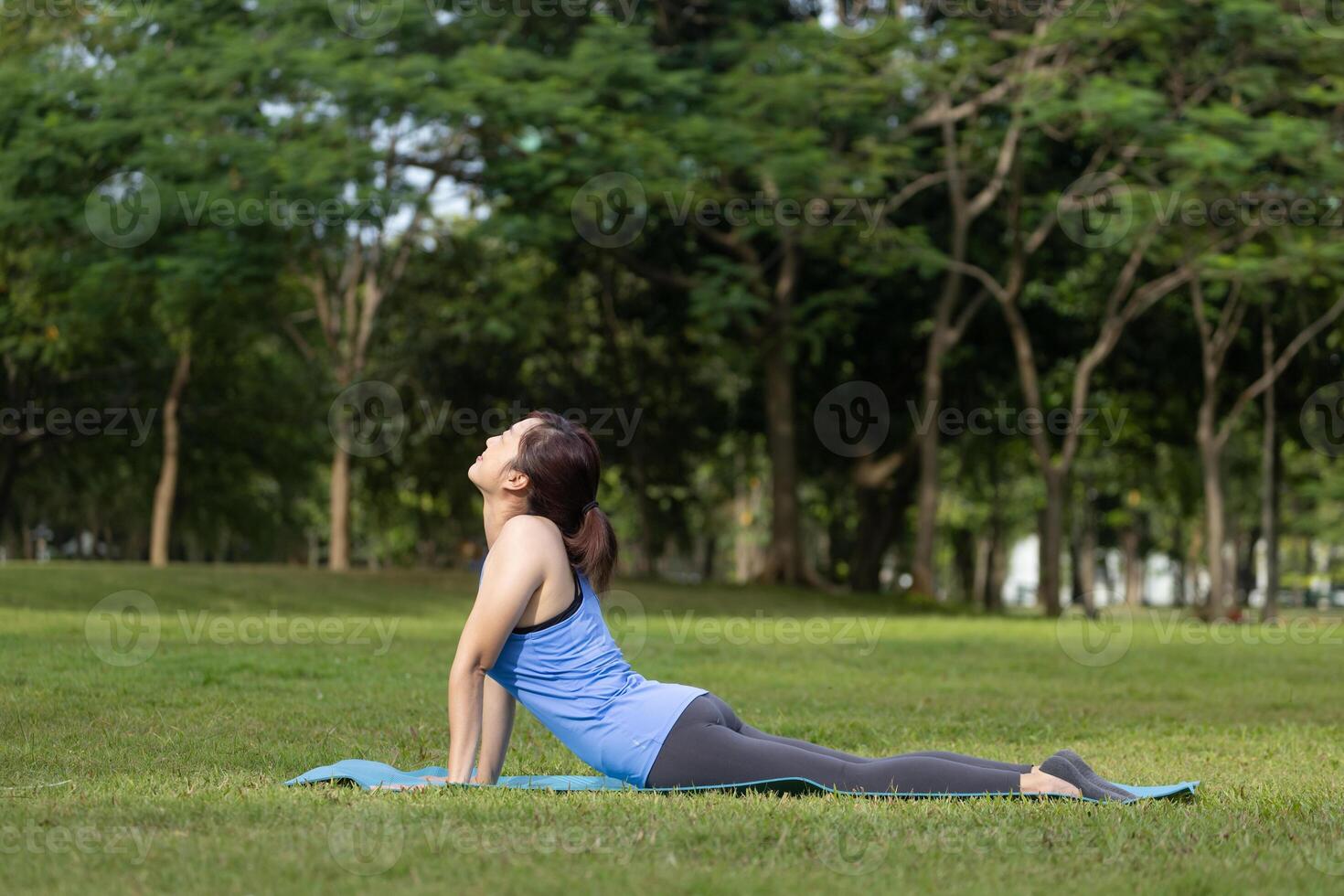 Asian woman relaxingly practicing cobra pose meditation yoga and stretching inside the forest to attain happiness from inner peace wisdom for healthy mind and soul concept photo