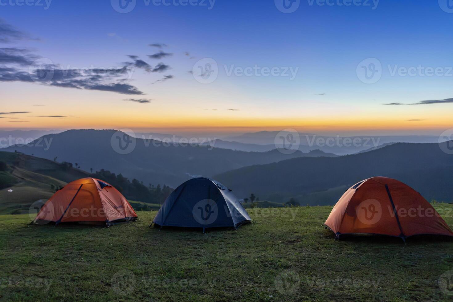Group of adventurer tents during overnight camping site at the beautiful scenic sunset view point over layer of mountain for outdoor adventure vacation travel concept photo
