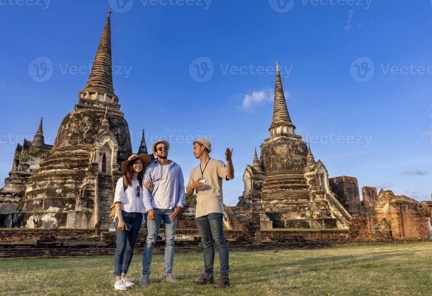 tailandés local excursión guía es explicando el historia de antiguo siam a el Pareja de turista en su mochilero Luna de miel viaje a antiguo templo de ayutthaya, Tailandia foto