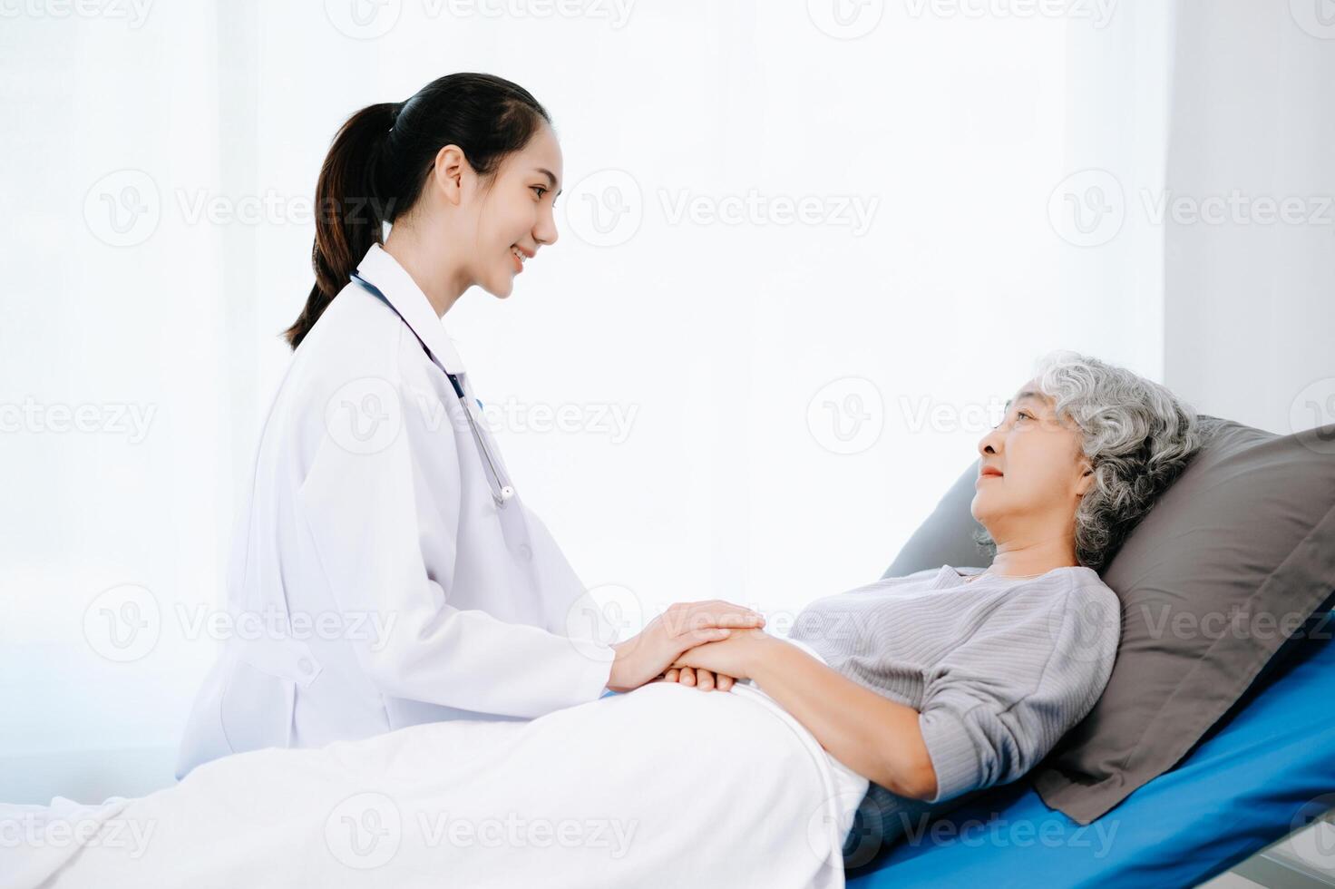 Doctor and Asian elderly patient who lie on the bed while checking pulse, consult and explain with nurse taking note in hospital wards. photo