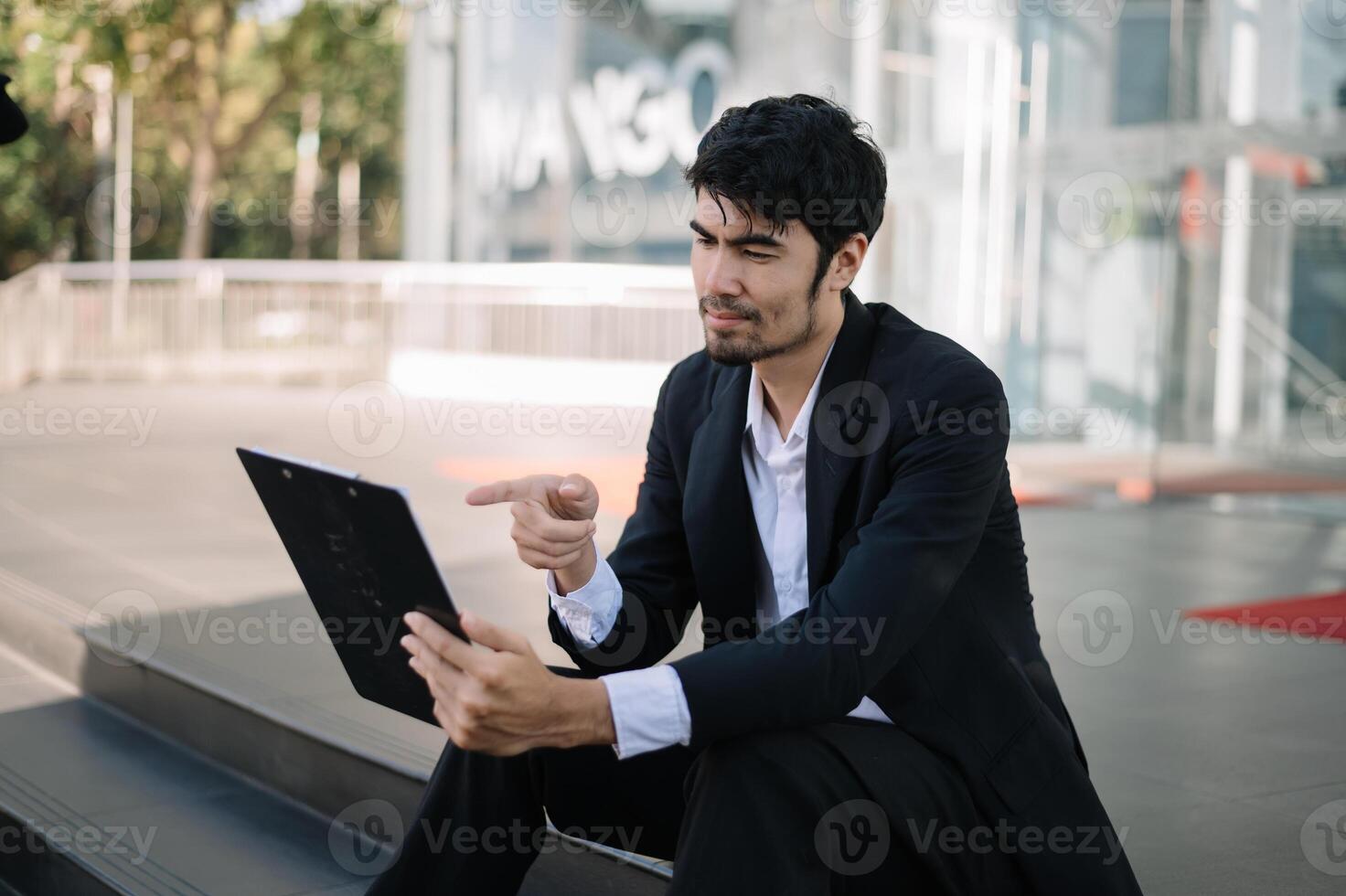 Young  businessman using a tablet on a bench in the city photo