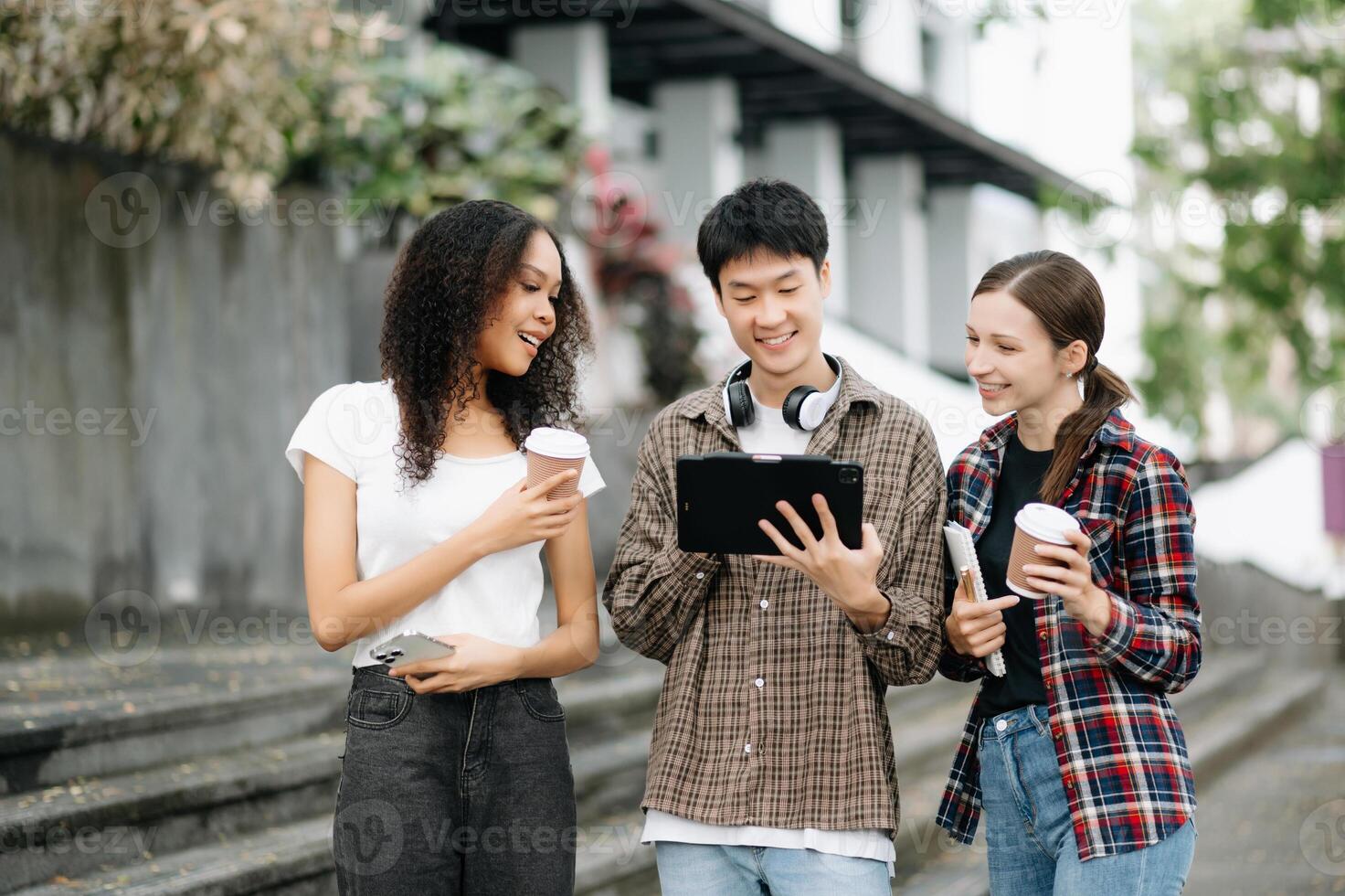 Students are studying the campus park. Young people are spending time together. Reading book, working with laptop, tablet and communicating while photo