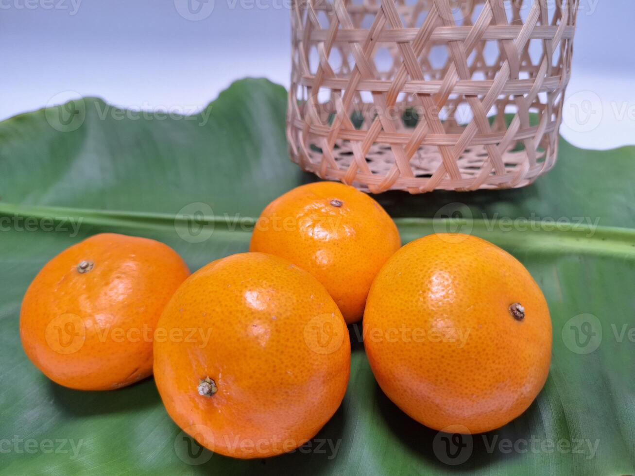 Image of oranges placed in a pile on banana leaves. photo