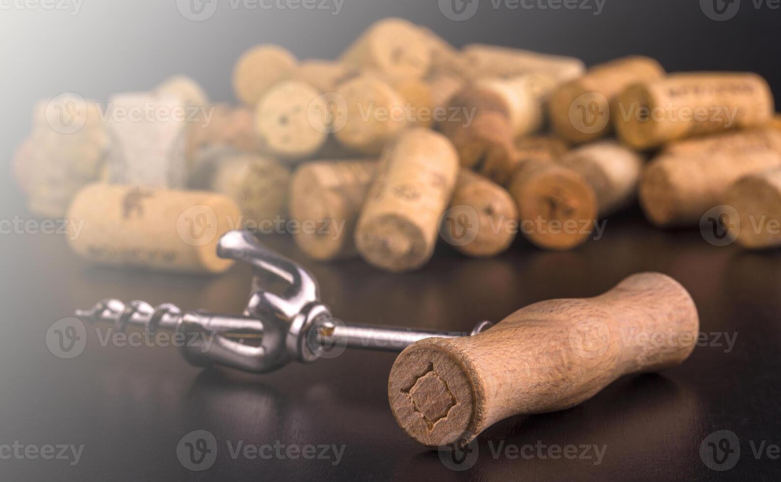 Wine corks and corkscrew on black wooden table in soft sunlight photo