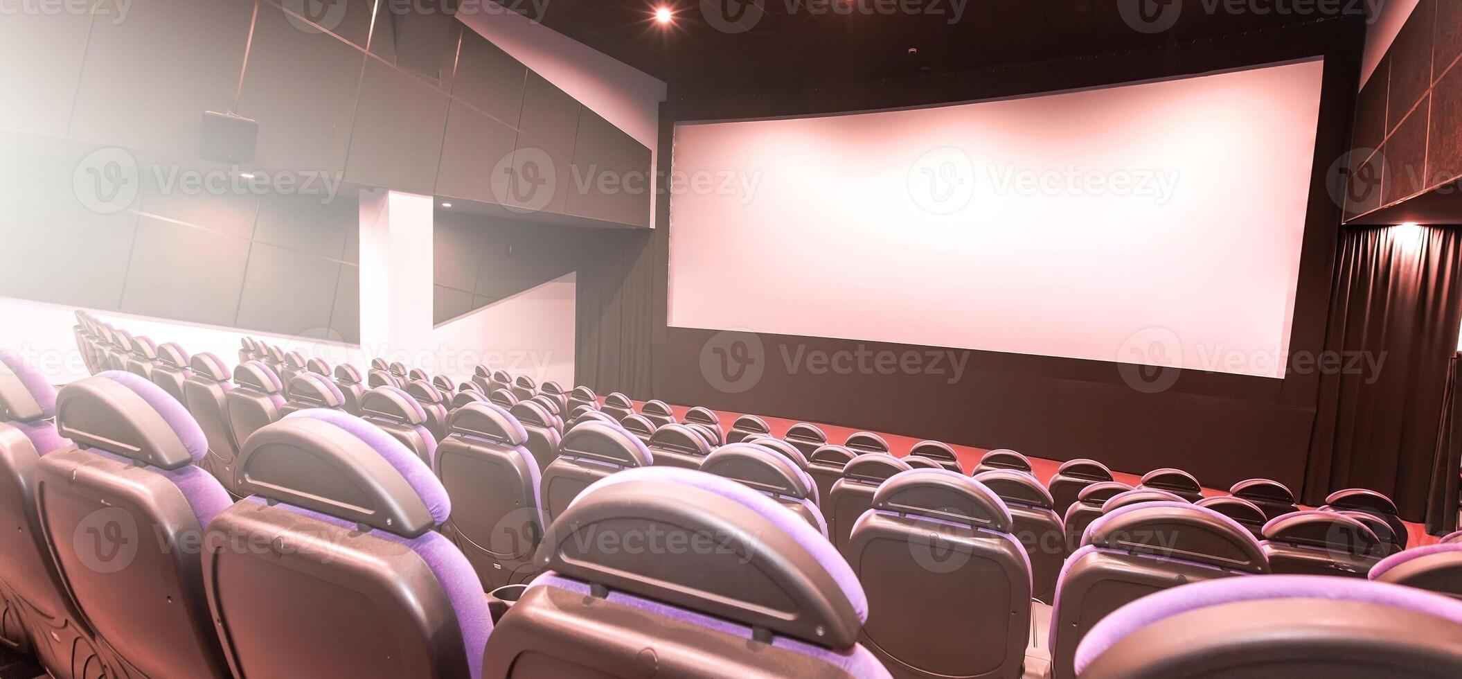 Cinema auditorium with line of red chairs, sitting visitors and silver screen. Ready for adding your own picture. photo
