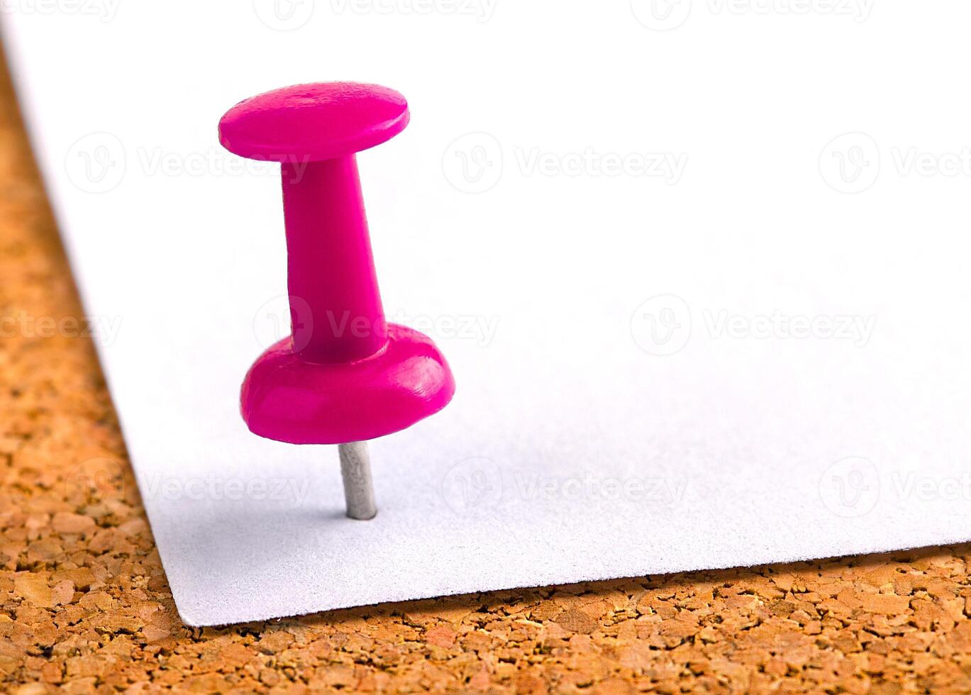 Plastic button with a needle stuck in an iron sheet of white paper on a wooden stopper photo