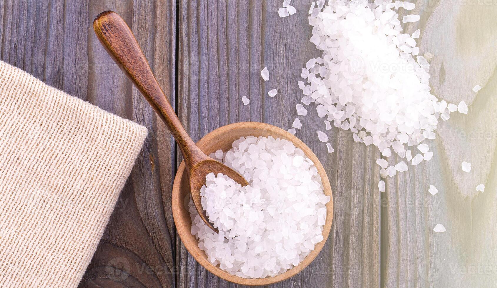 Sea salt on cup, spoon and burlap on a wooden table photo