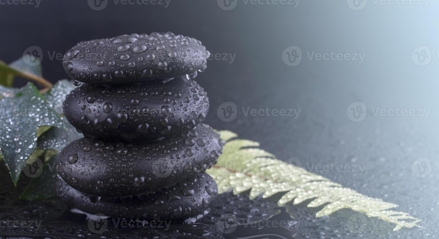 Stacked wet spa stone with green leaf. selective focus.tone image on sunlight photo