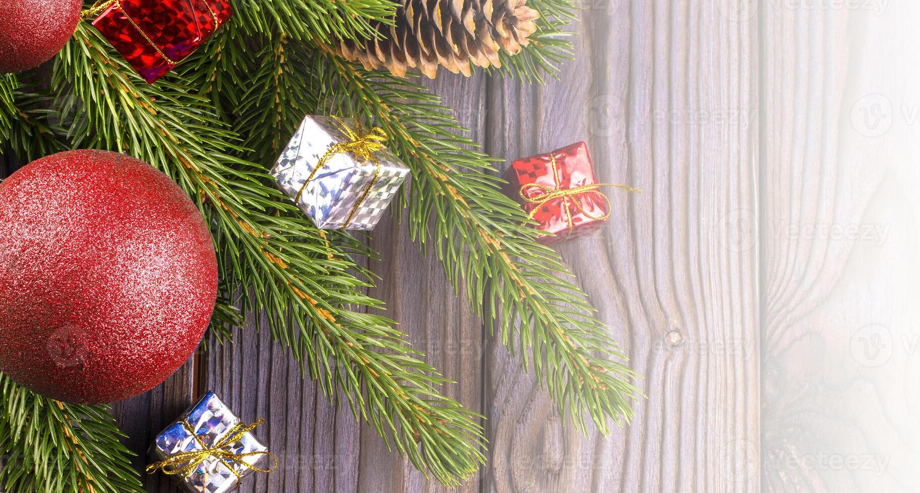 Branches of a Christmas tree decorated with red ball and toys with silk on a wooden table on sunlight photo