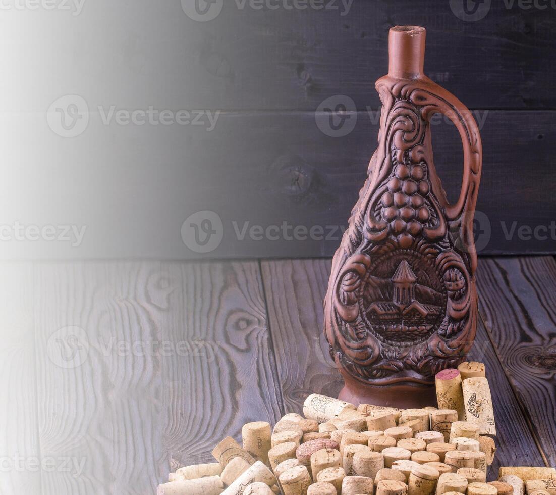 Clay bottle of wine and cork on a dark wooden table on soft sunlight photo