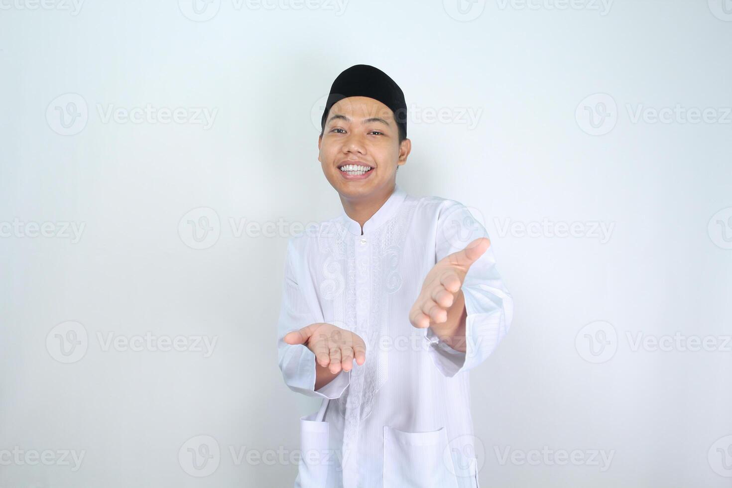 attractive muslim asian man presenting hand forward at camera with smiling face isolated on white background, looking at camera photo