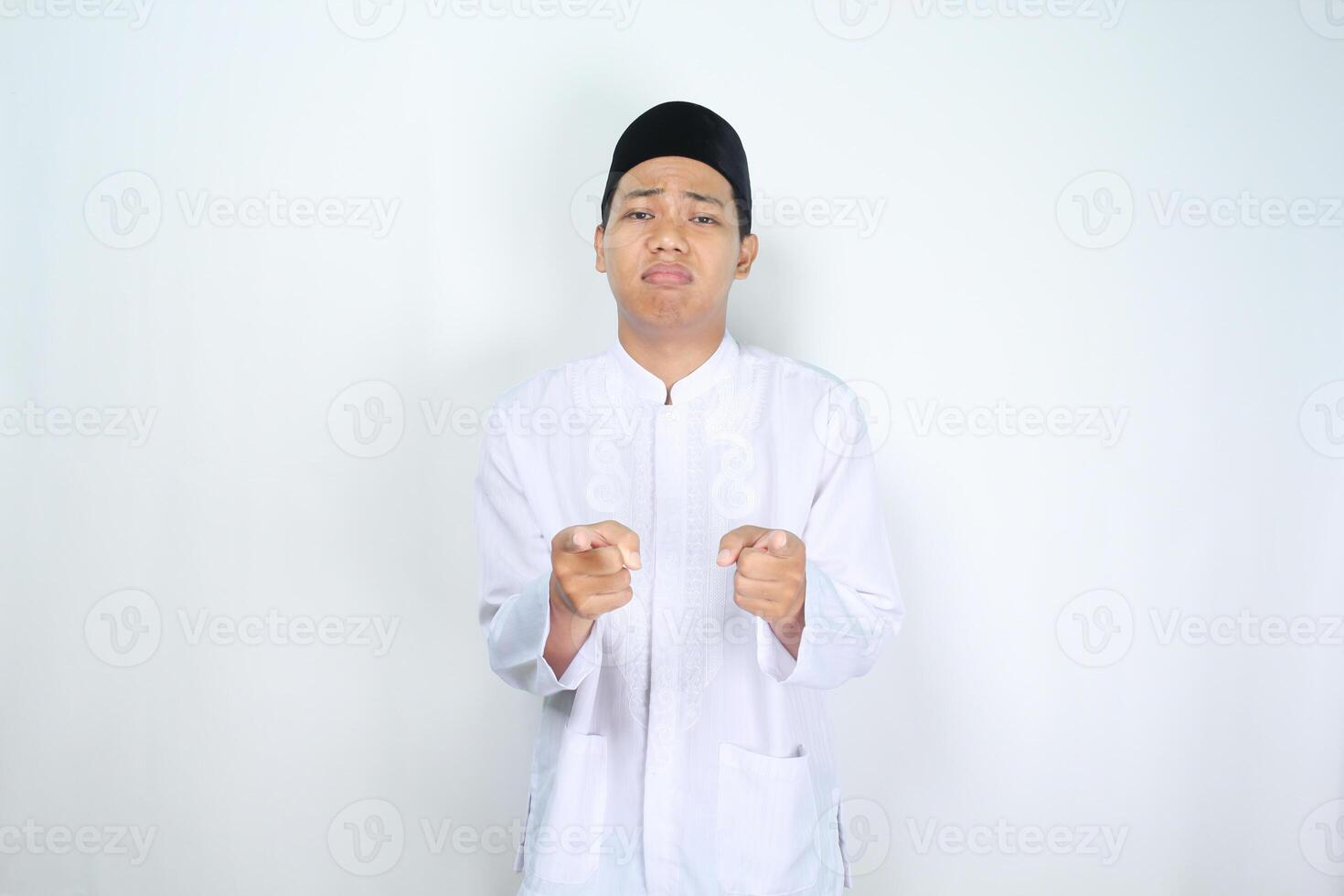 muslim asian man pointing forward to camera with sad expression isolated on white background photo