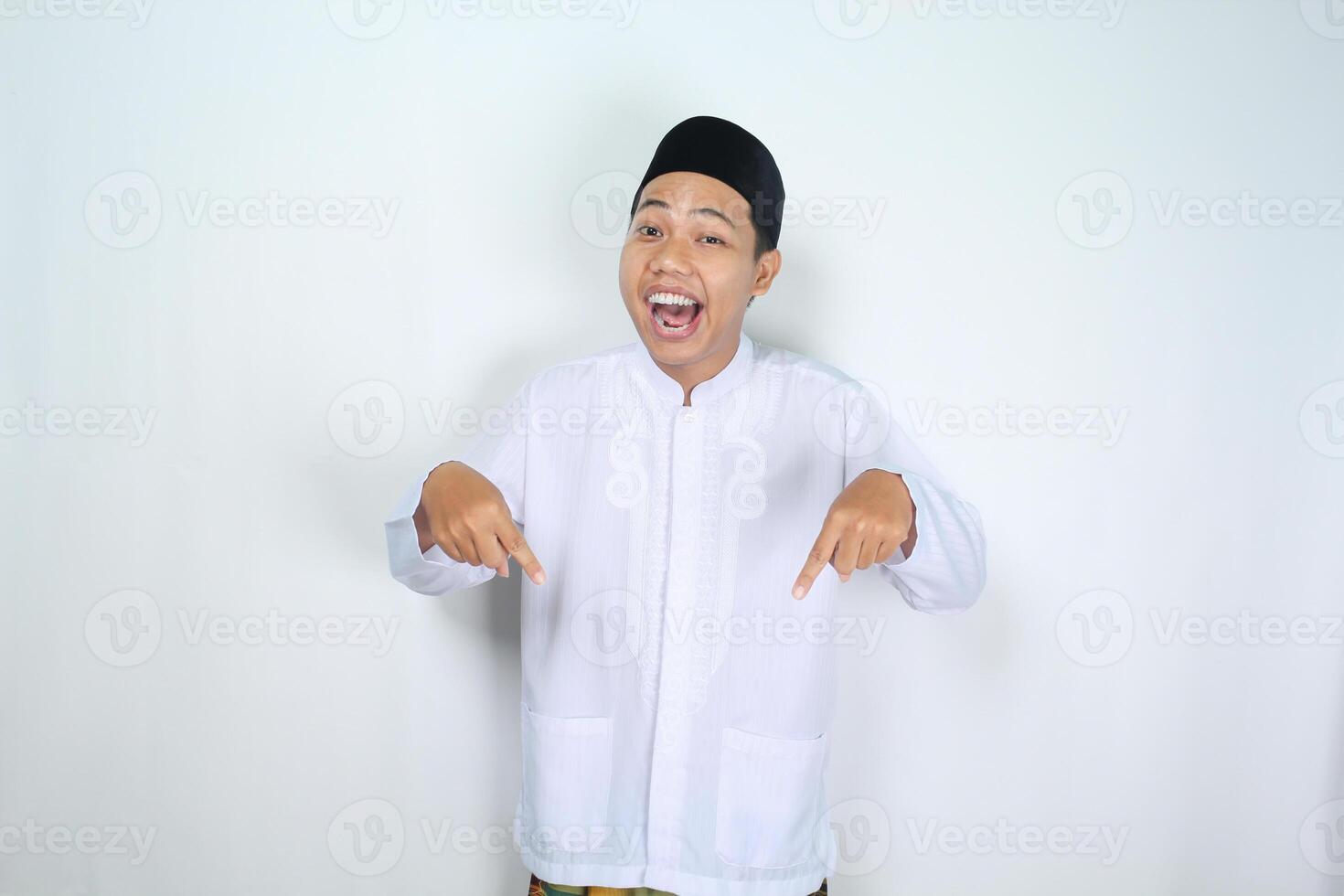 attractive muslim asian man pointing down and shouting with mouth open isolated on white background photo