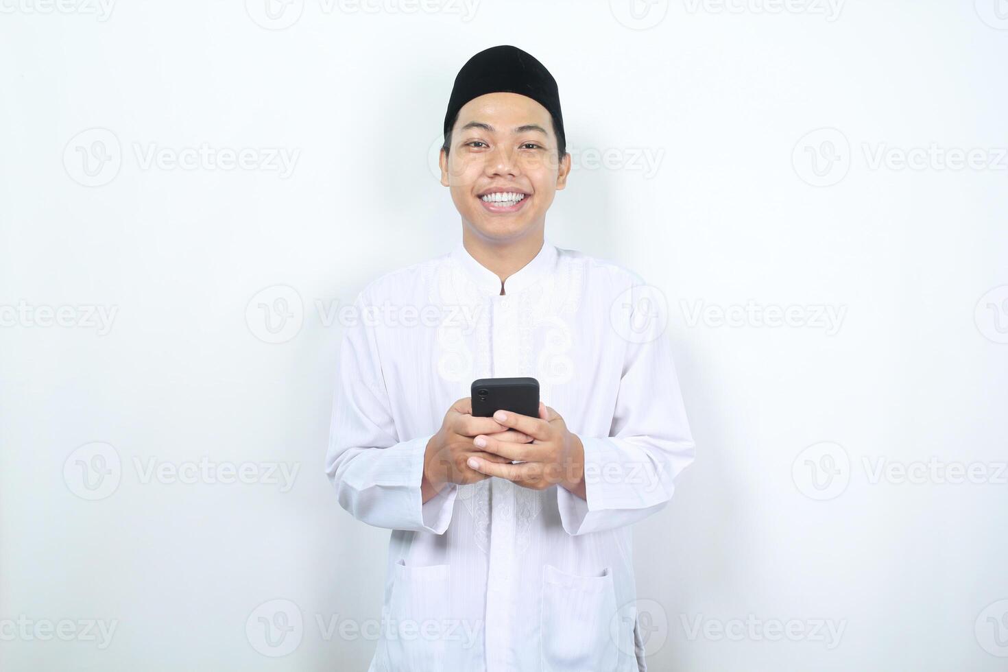 contento musulmán hombre asiático participación teléfono y mirando a cámara con sonrisa foto