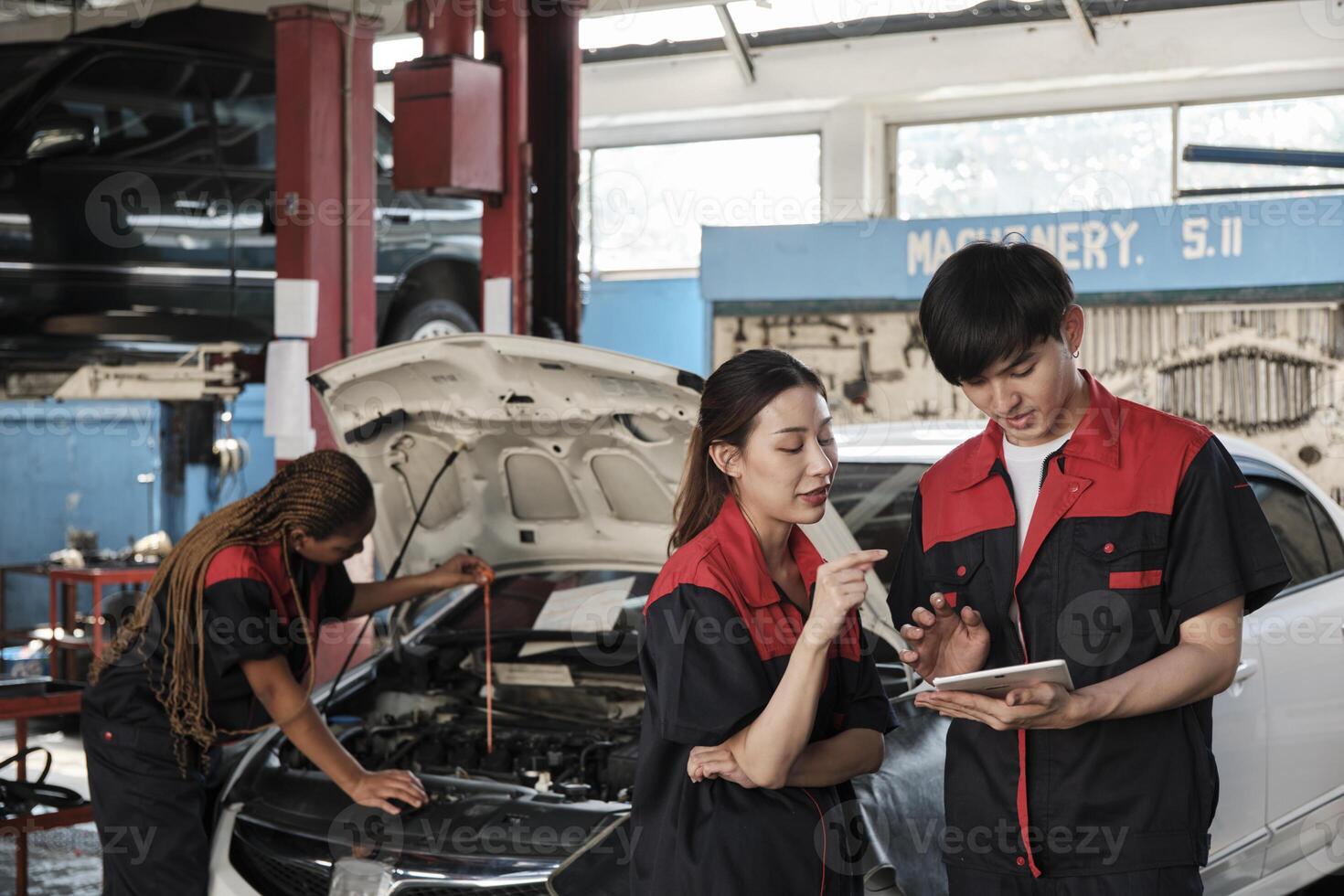 Two Asian professional mechanics, male supervisor engineer, and partner discuss and inspect repair work checklists at garage, service car maintenance, and fixing specialist occupations auto industry. photo