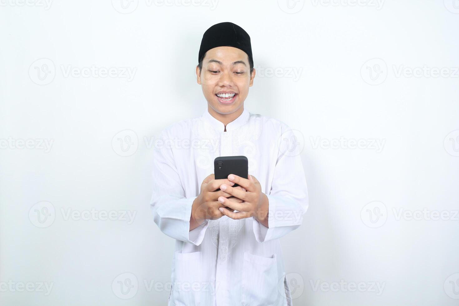 happy asian muslim man smiling while looking at his phone photo