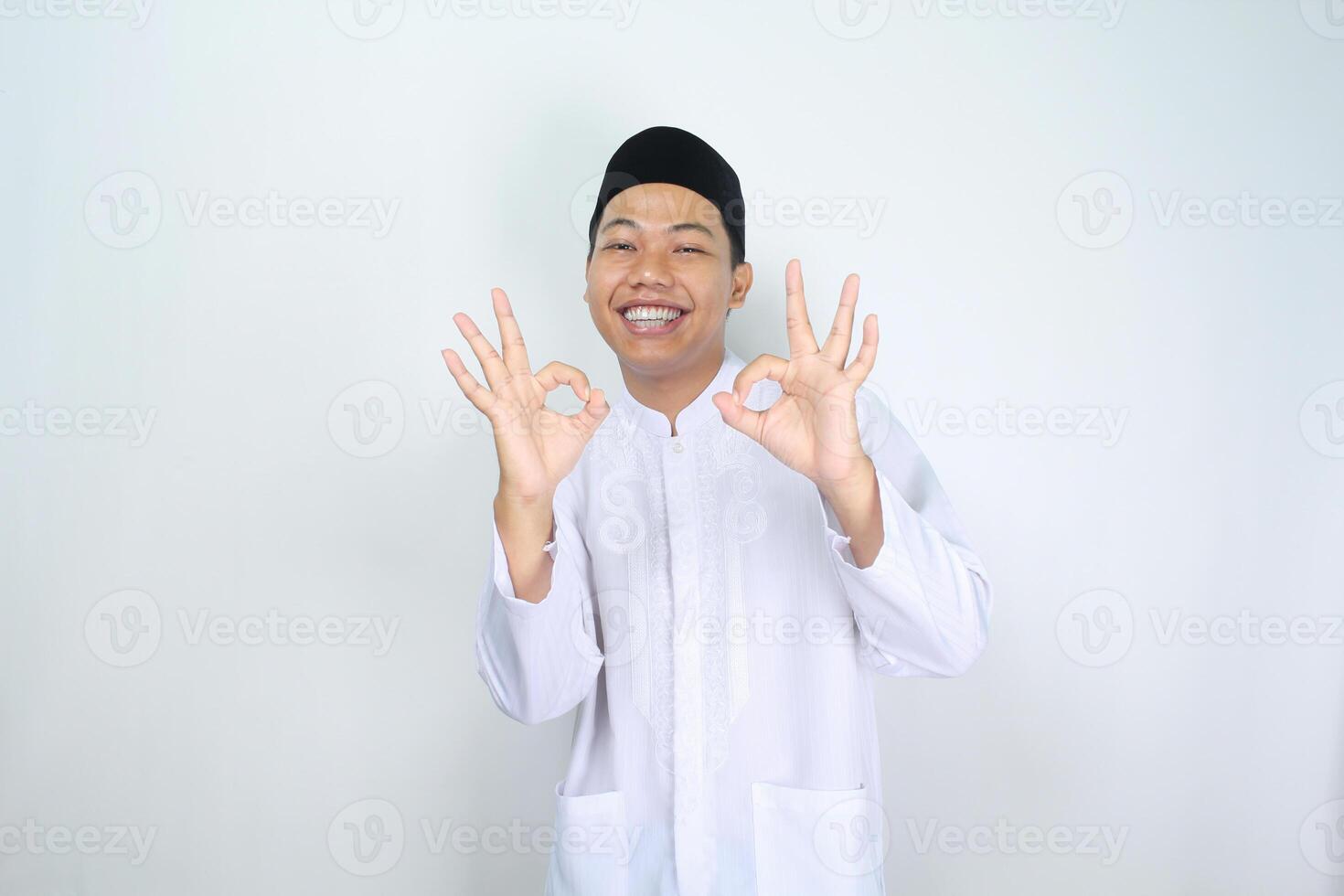 sonriente asiático hombre musulmán espectáculo Okay señales aislado en blanco antecedentes foto