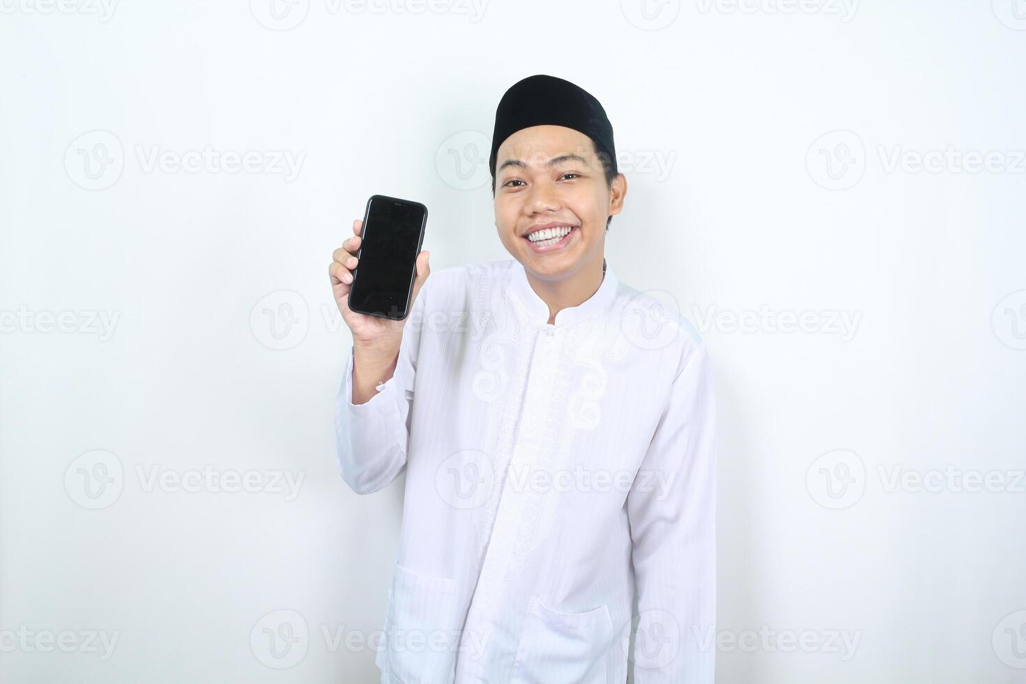 smiling asian muslim man showing blank phone screen isolated photo