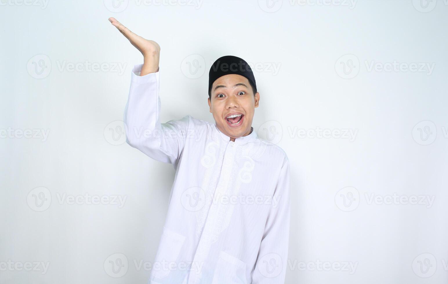 funny asian muslim man with surprised expression raising hand to presenting isolated on white background photo