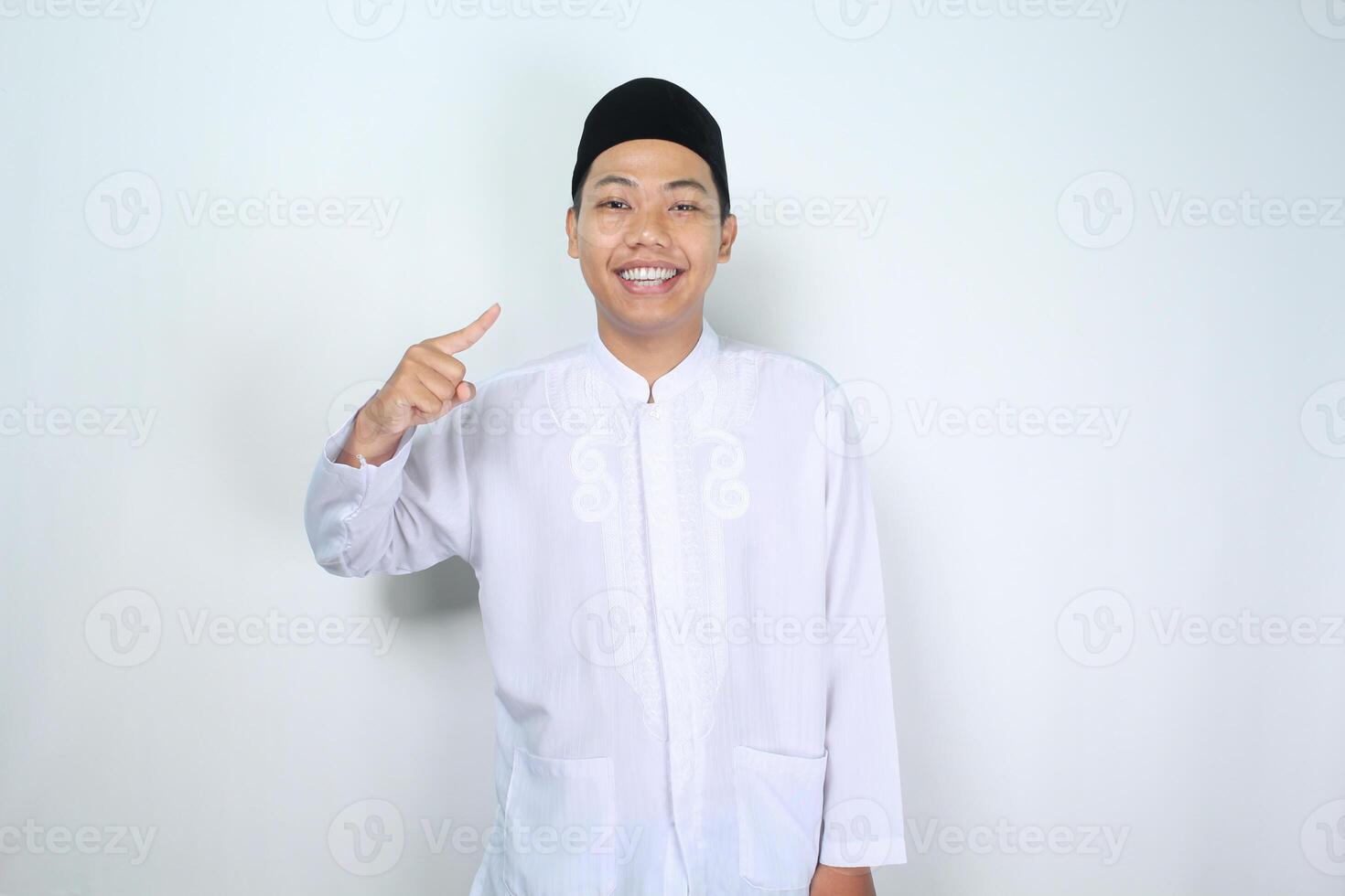 alegre musulmán asiático hombre señalando a él yo con sonriente a cámara, espectáculo sus yo gesto, aislado en blanco antecedentes foto