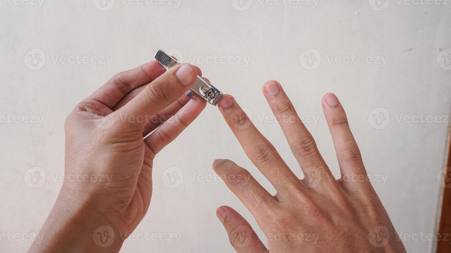 close up hand care with nail clipper. man is cleaning and cutting nails photo