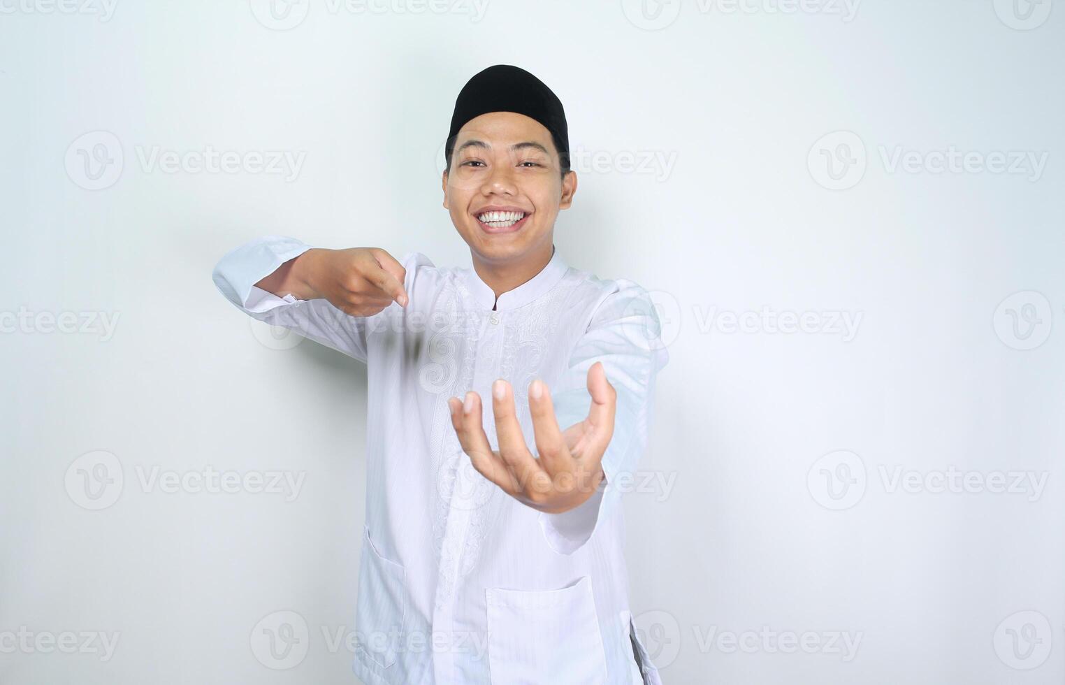 happy muslim asian man pointing to empty hand, imagine holding bowl, isolated on white background photo