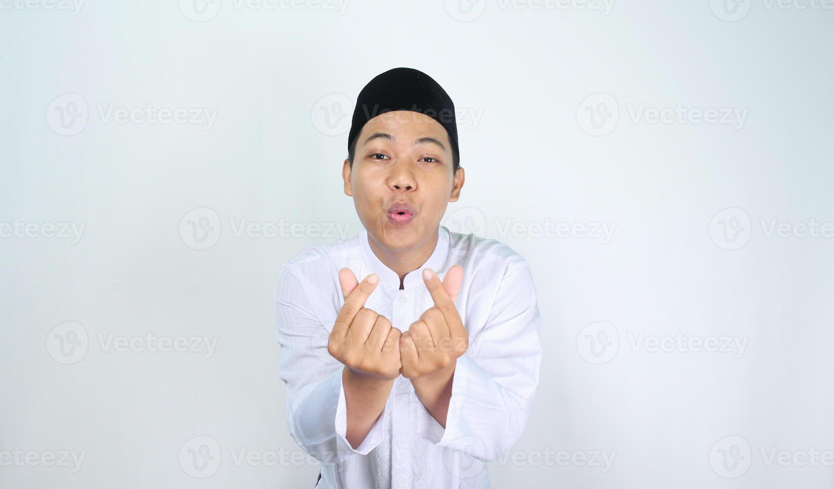 happy asian man muslim blowing kiss with finger shaped korean love sign to camera isolated on white background photo