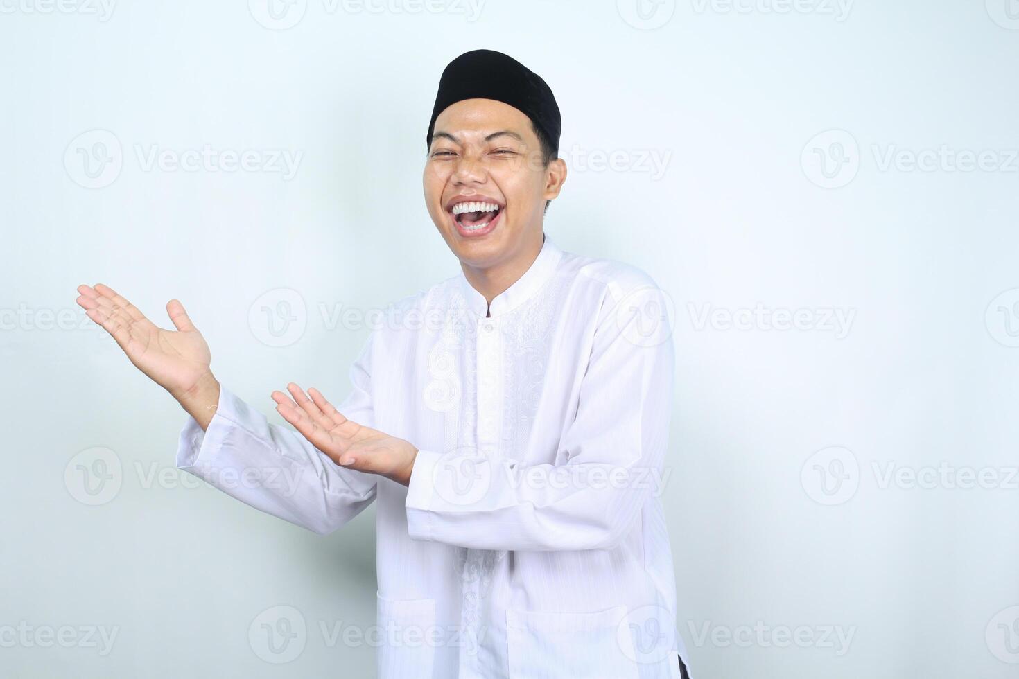 portrait of laughing asian muslim man presenting to side isolated on white background photo