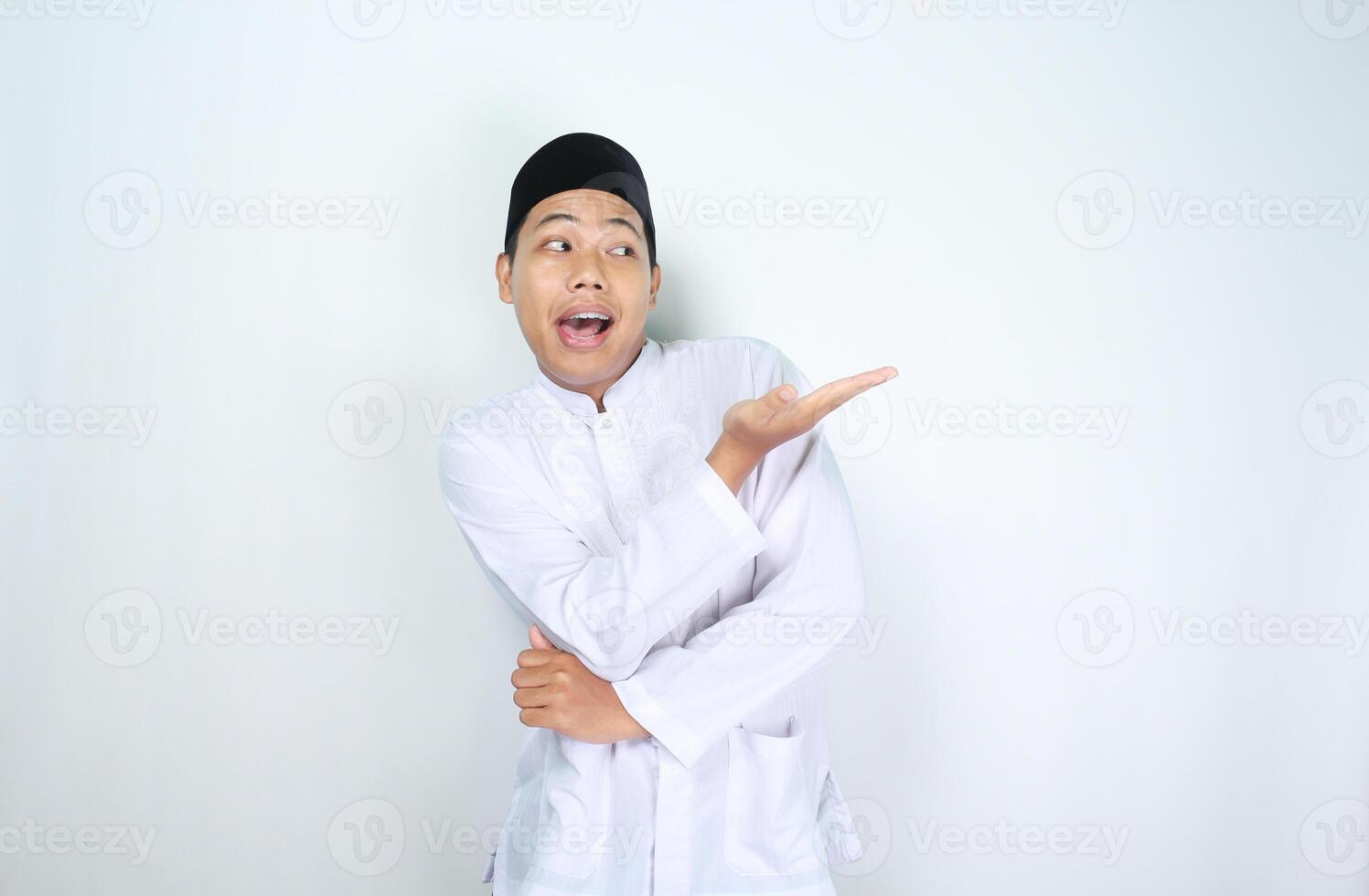 funny asian muslim man with surprised expression presenting hand to beside isolated on white background photo